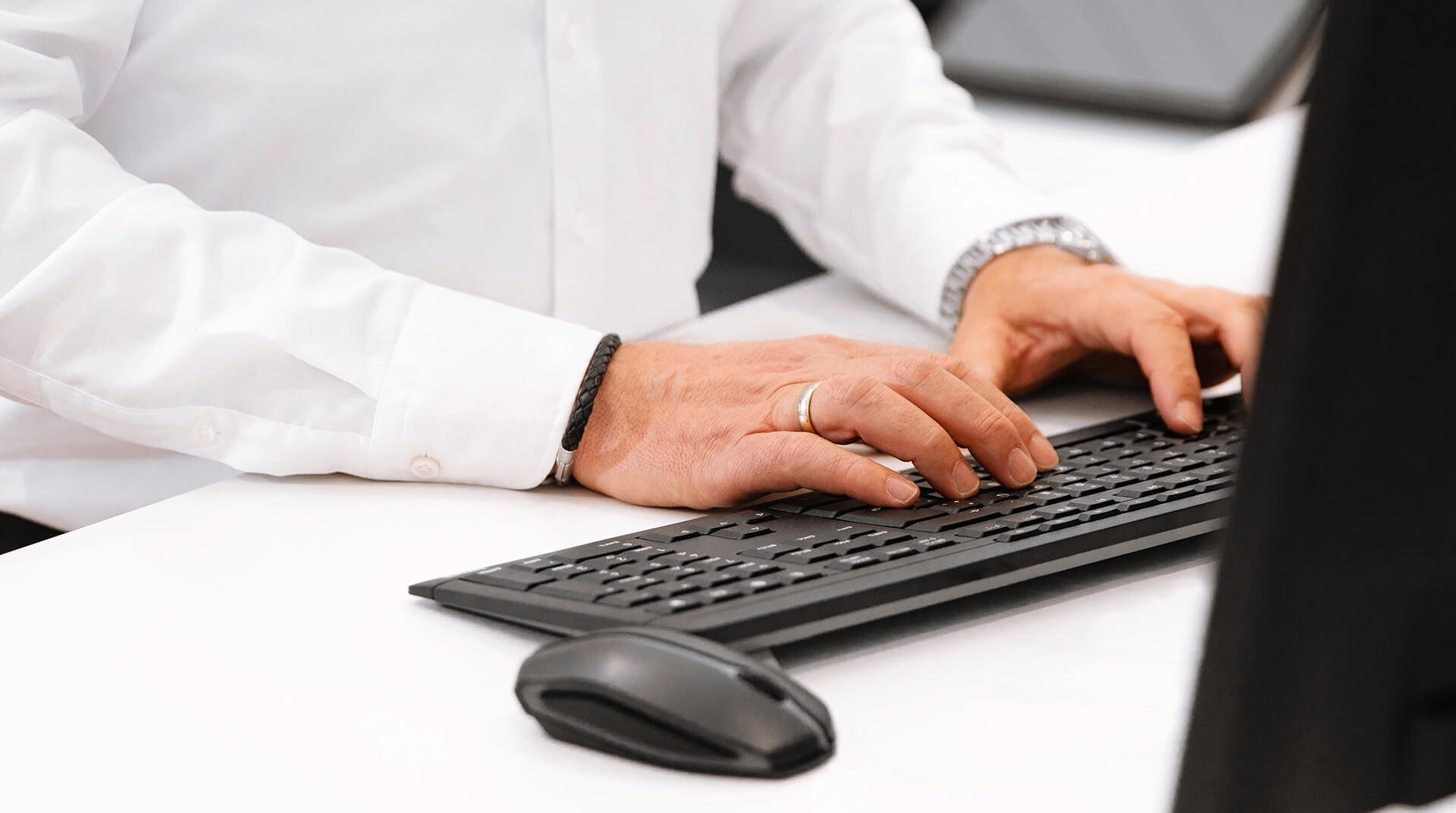 Mann mit Hemd tippt auf Tastatur am PC